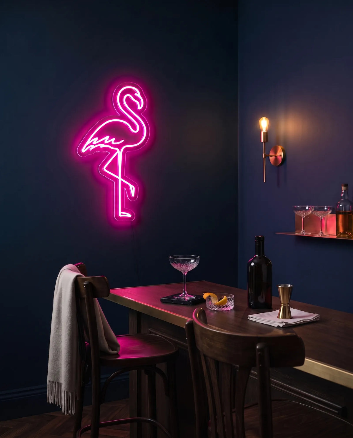Néon flamant rose sur mur bleu nuit, comptoir de bar en bois avec cocktail et applique en laiton