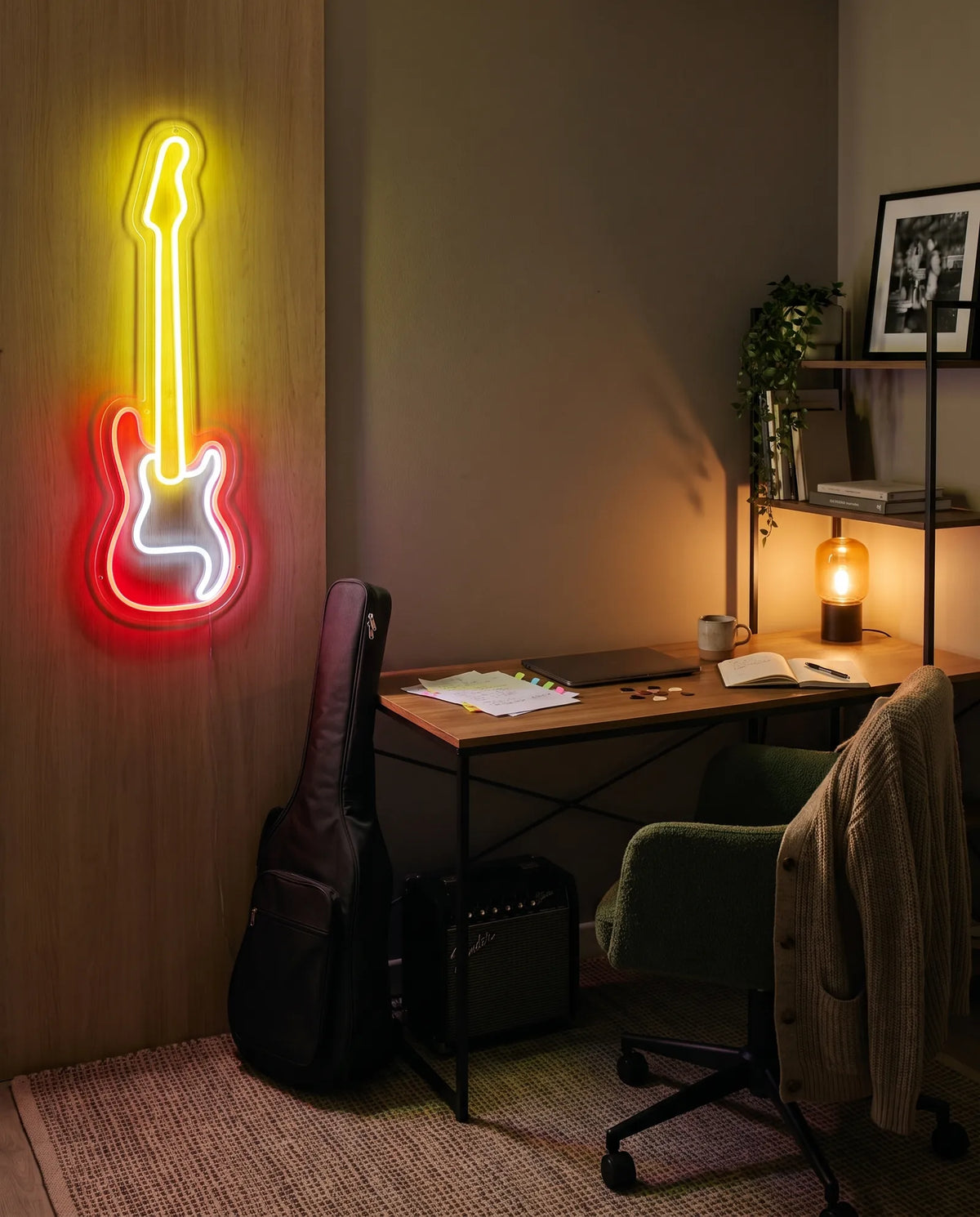 Néon guitare sur panneau en bois dans un bureau de musicien, housse de guitare, ampli et médiators sur le bureau