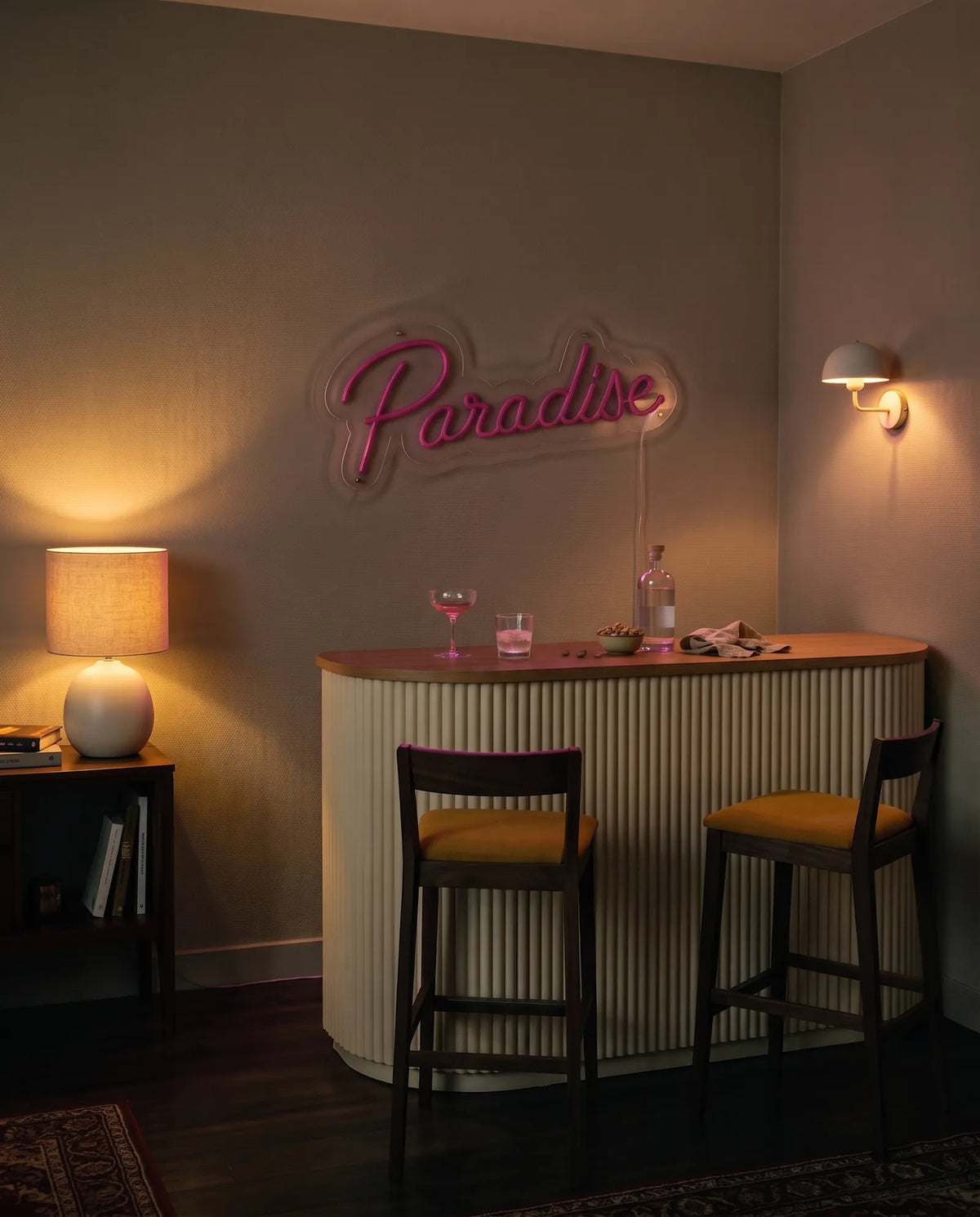 Néon paradise éteint dans un coin bar le soir, comptoir cannelé, tabourets et lampe allumée
