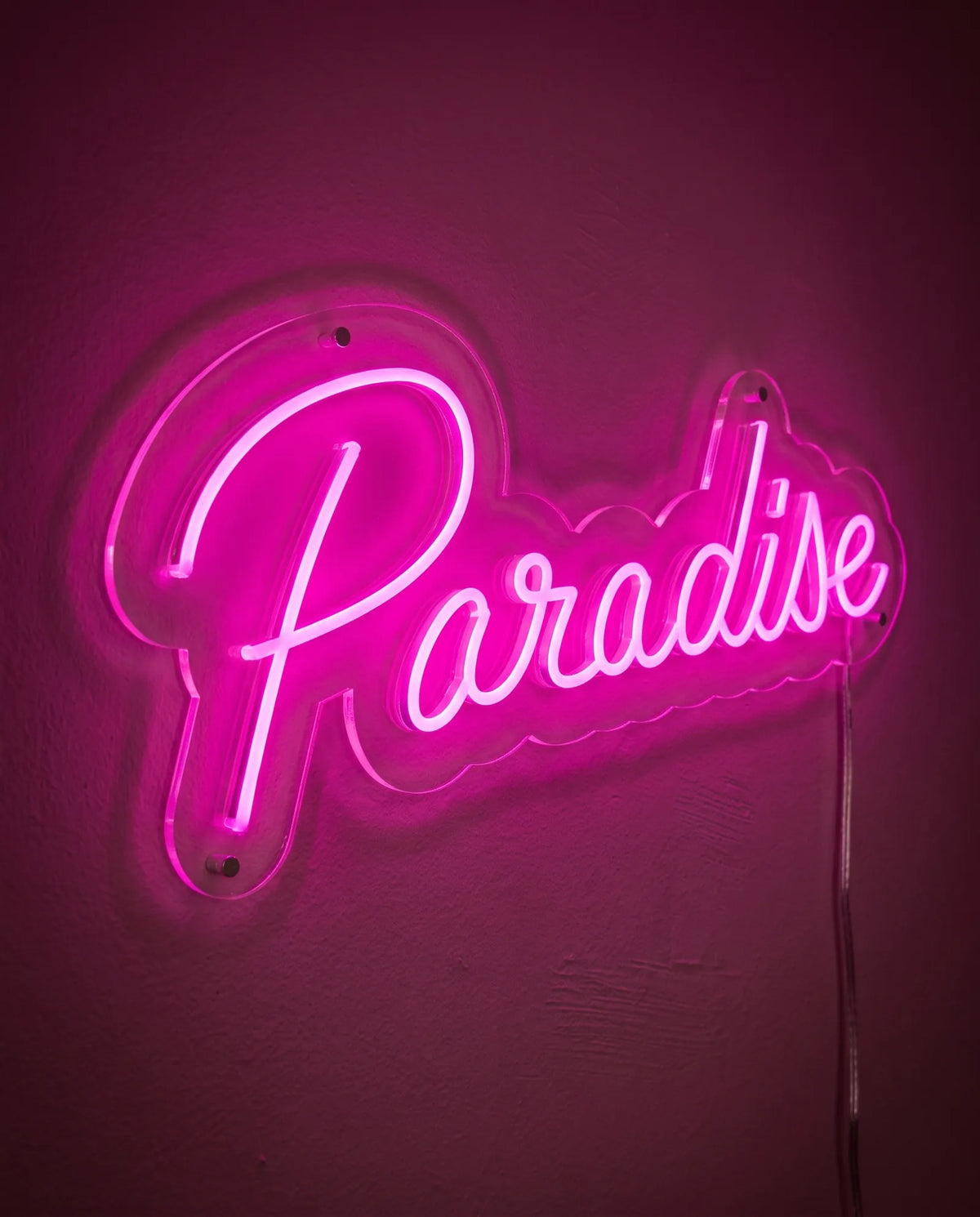 Néon LED vu de trois-quarts, plexiglas cristallin découpé en vagues autour du mot paradise