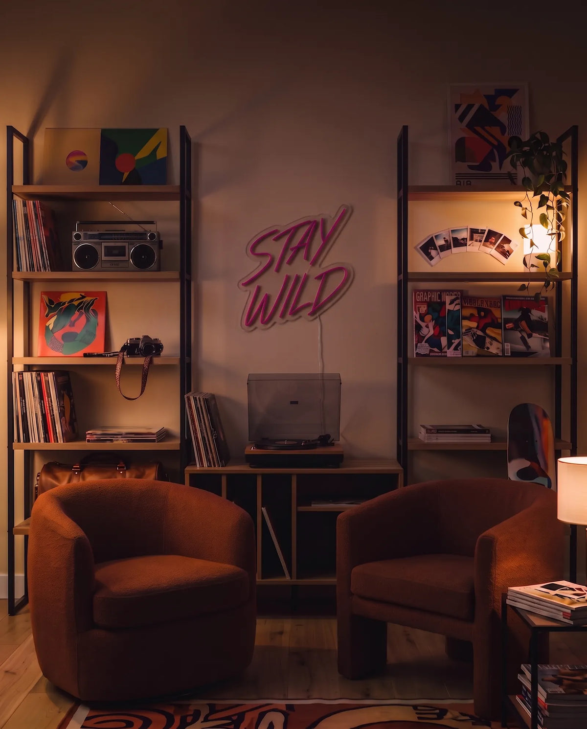 Néon Stay Wild éteint dans un salon le soir, étagères de vinyles, polaroïds et fauteuils en bouclette