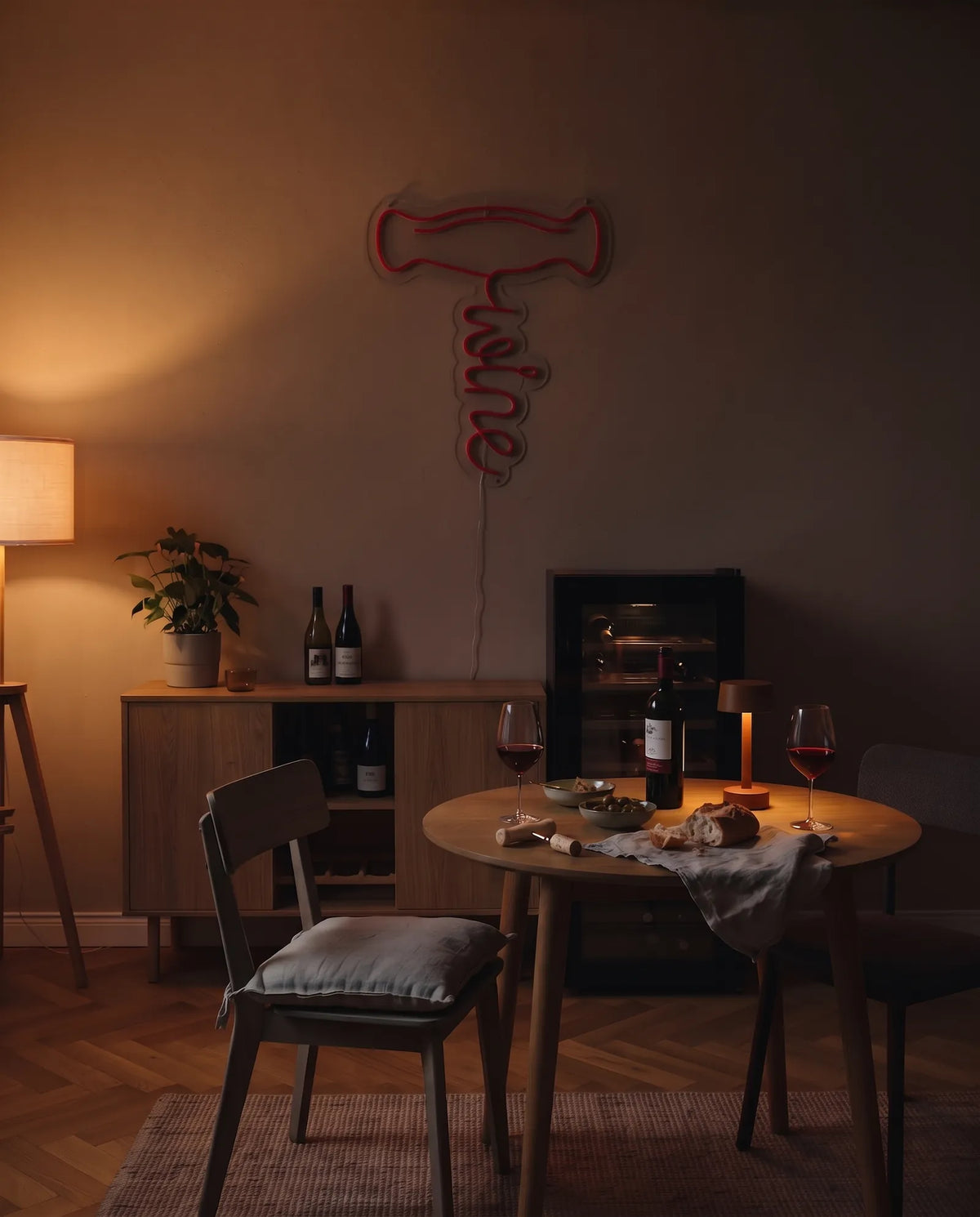Néon tire-bouchon éteint dans un coin bar le soir, buffet en bois, lampadaire et table dressée pour deux