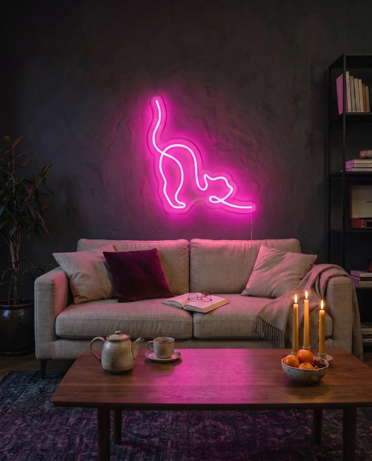 Néon LED chat rose qui s’étire, allumé au-dessus d’un canapé en lin, table basse avec théière et bougies