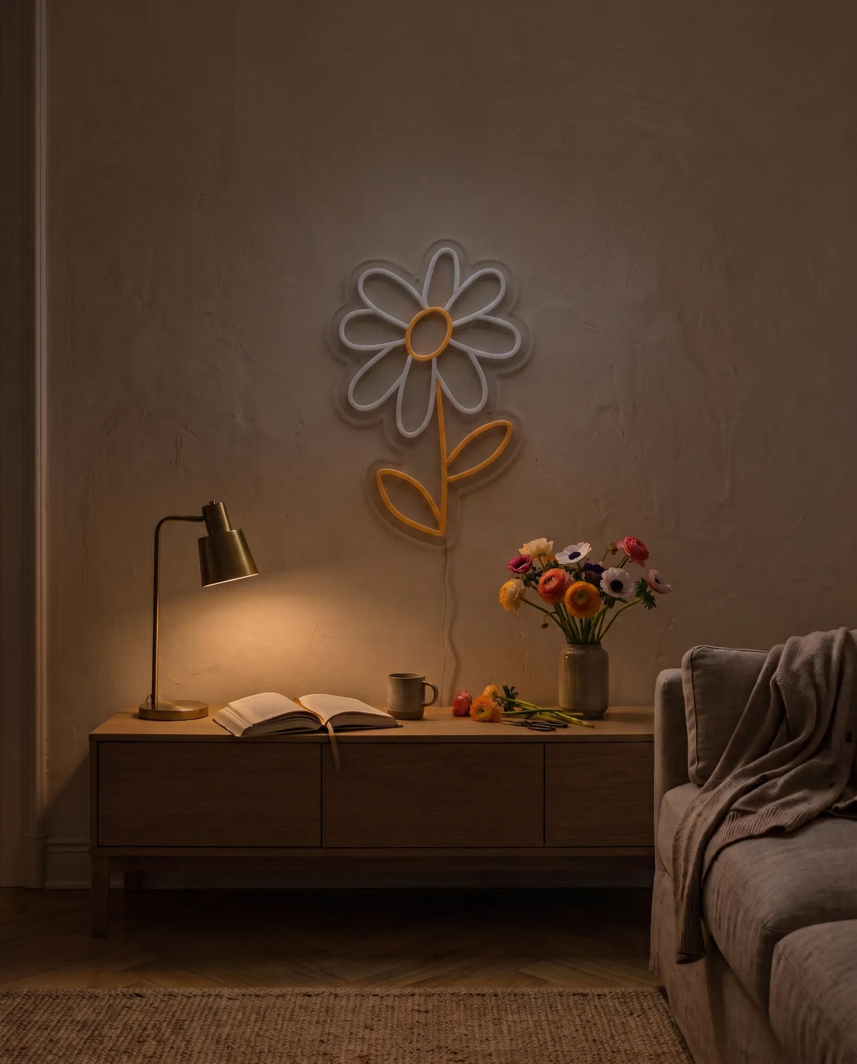 Néon marguerite éteint au-dessus d’une console de salon le soir, lampe dorée et vase de fleurs fraîches