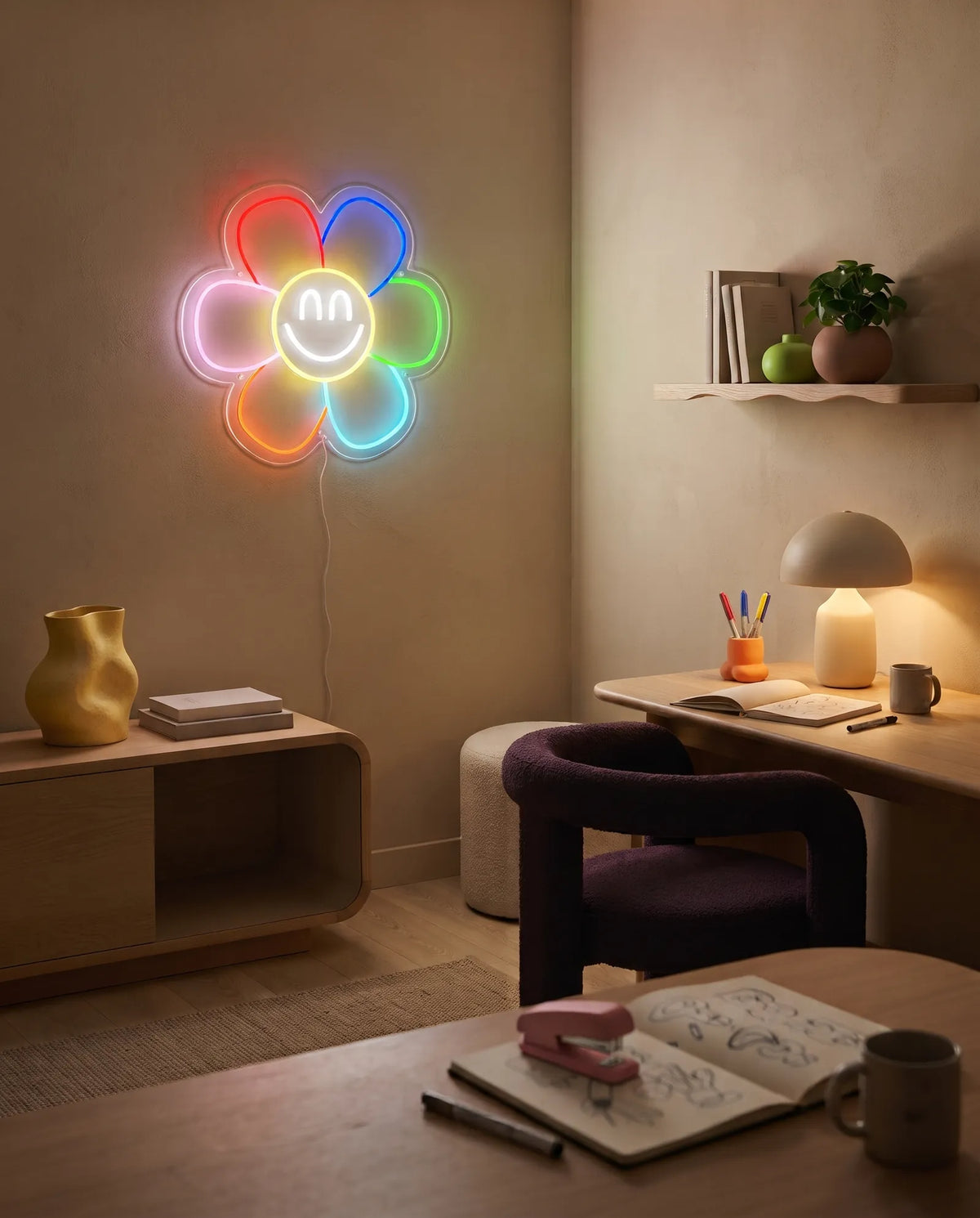 Néon fleur smiley au-dessus d’un bureau créatif, carnet de croquis, lampe champignon et chaise prune