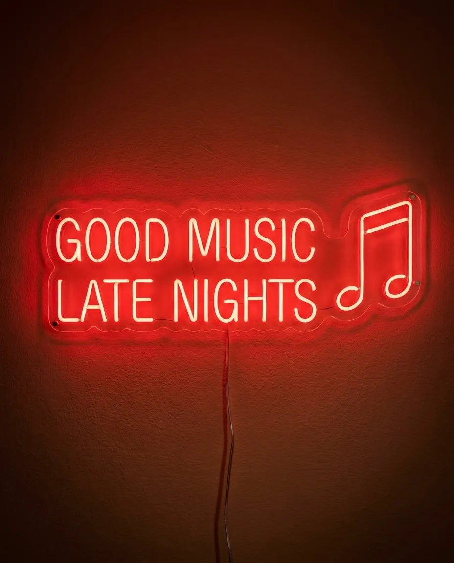 Néon Good Music Late Nights de face sur mur peint, lettres rouges sur deux lignes et une croche