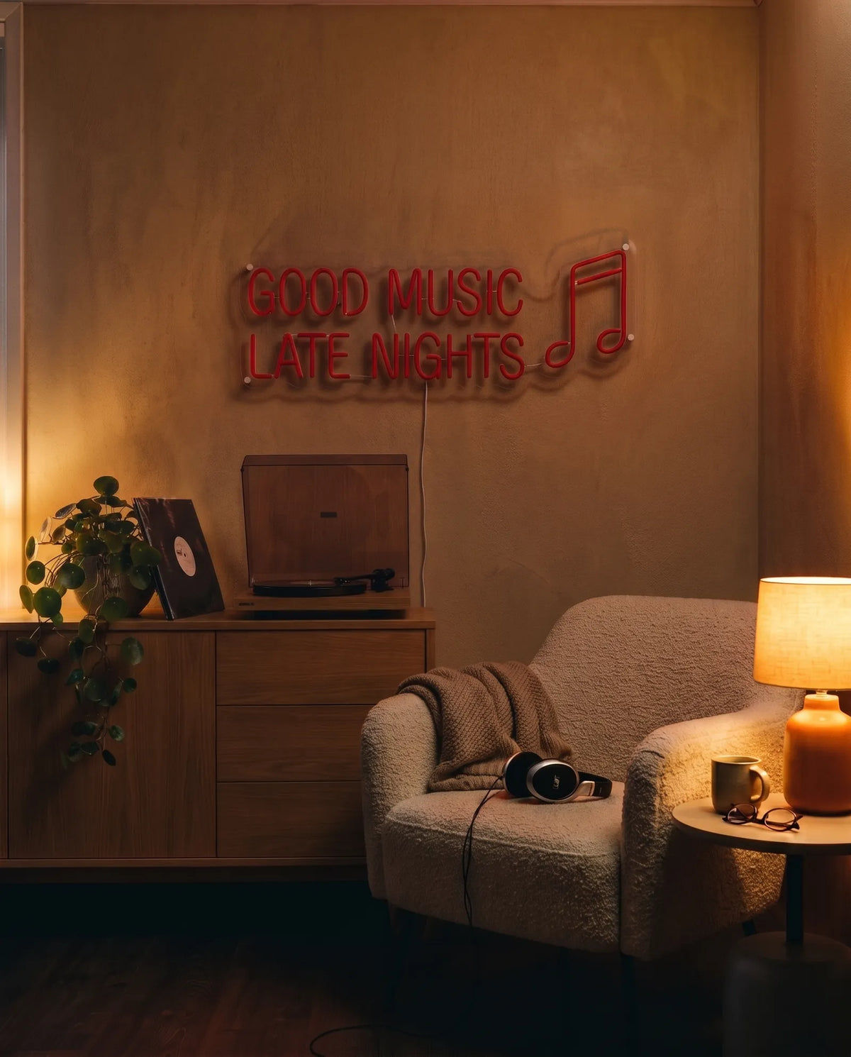 Néon Good Music Late Nights éteint dans un salon le soir, buffet en bois, platine et fauteuil