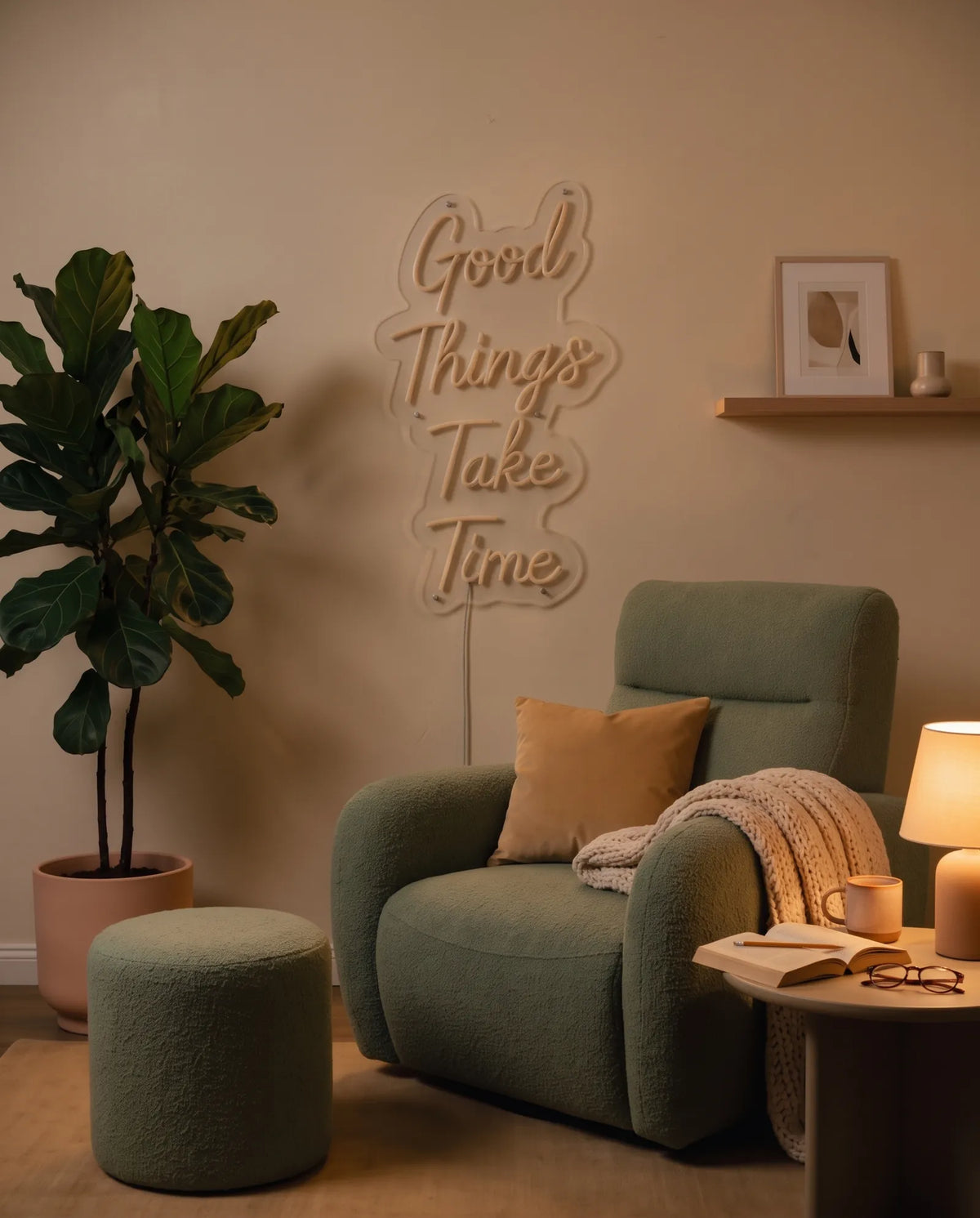 Néon Good Things Take Time éteint dans un salon le soir, fauteuil en bouclette, plante et lampe