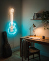 Néon guitare acoustique turquoise au-dessus d’un bureau en bois, partition ouverte et lampe en laiton allumée