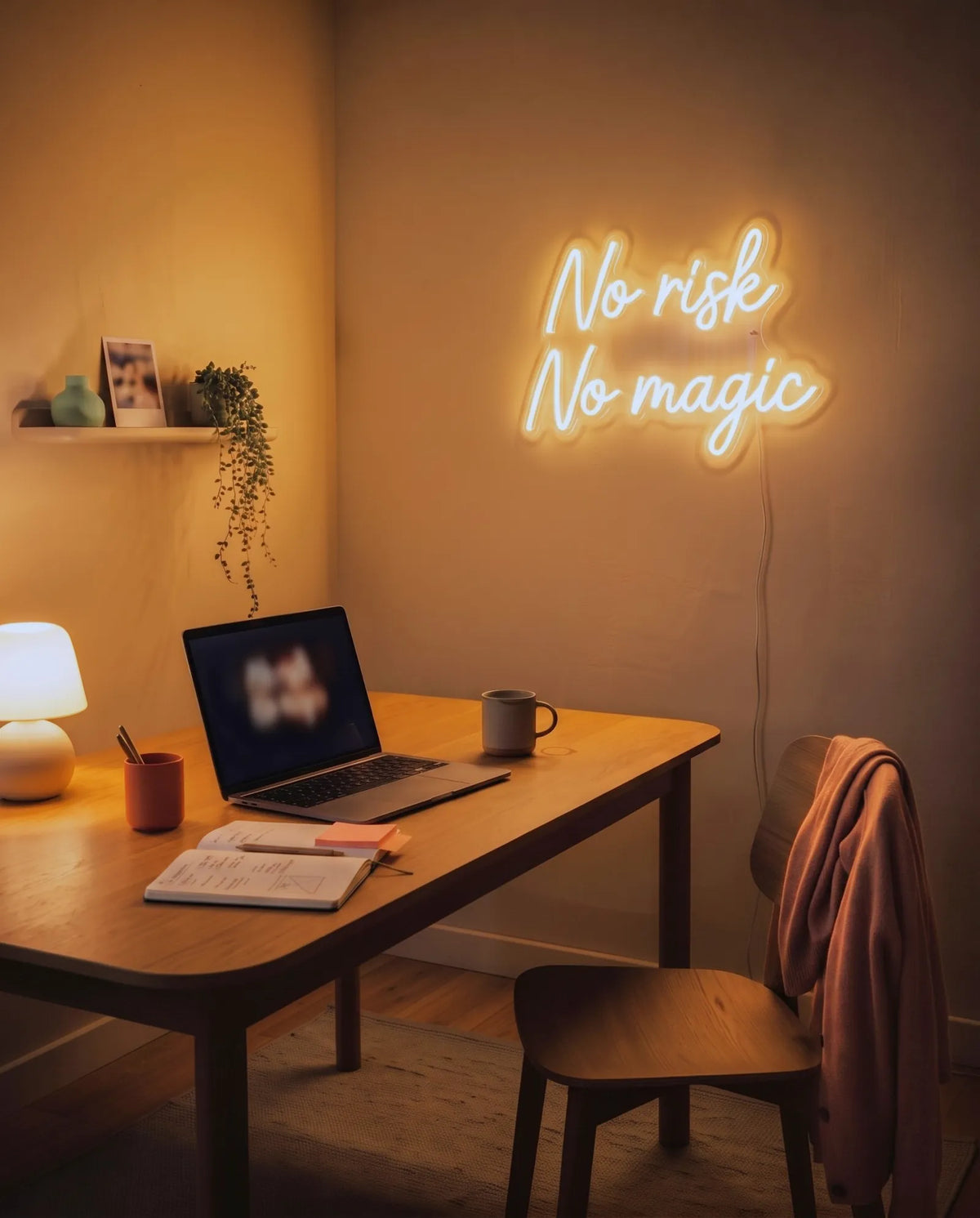 Néon LED citation No Risk No Magic près d’un bureau en bois, ordinateur, carnet et lampe boule