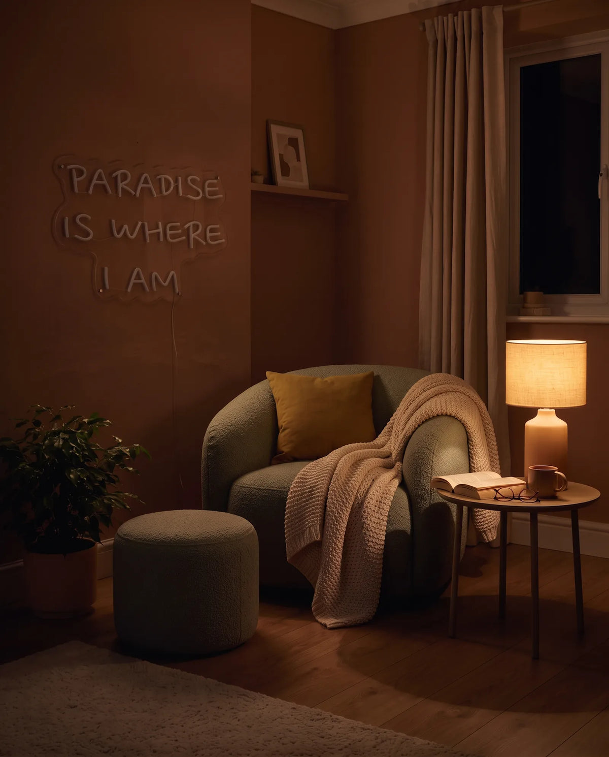 Néon Paradise Is Where I Am éteint dans un salon le soir, fauteuil, lampe allumée et rideaux tirés