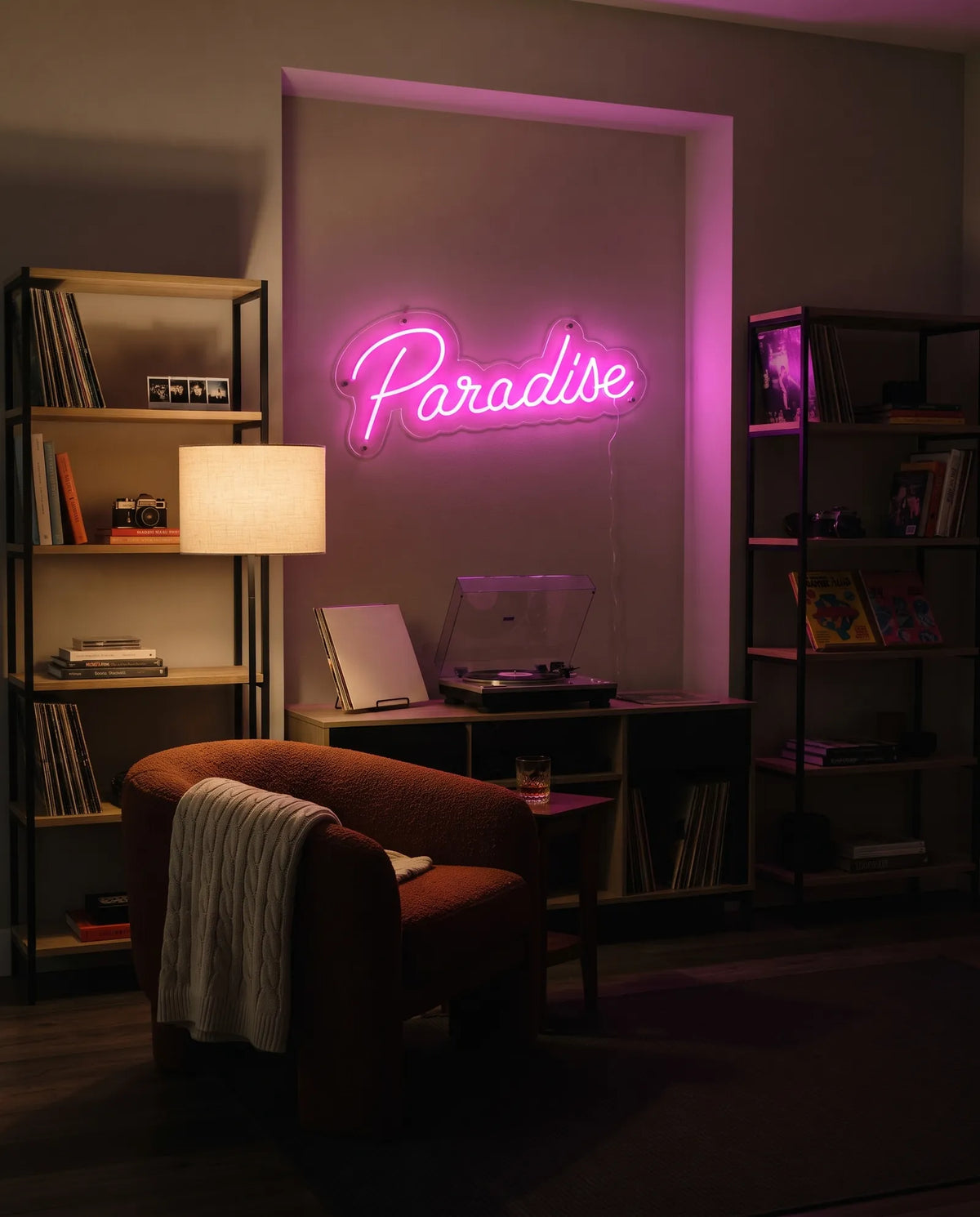 Néon LED paradise dans un salon, fauteuil bouclette rouille, platine vinyle et étagères de disques