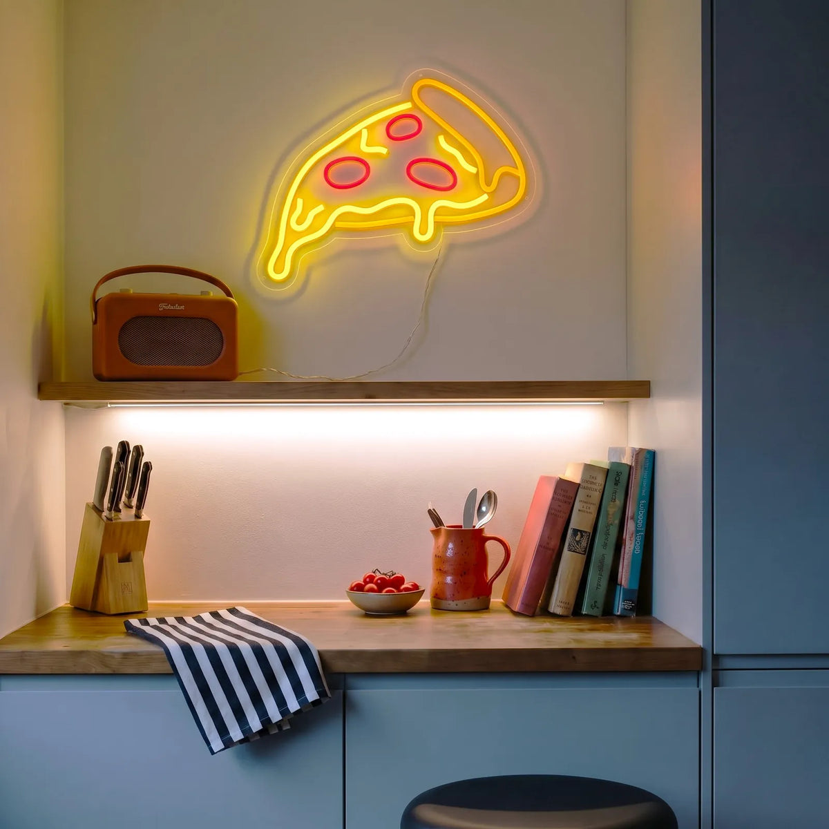Néon LED part de pizza au-dessus d’une étagère de cuisine, radio vintage et livres de recettes
