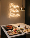 Néon LED pizza pasta au-dessus d’un îlot en marbre, sauce tomate, tagliatelles fraîches et basilic