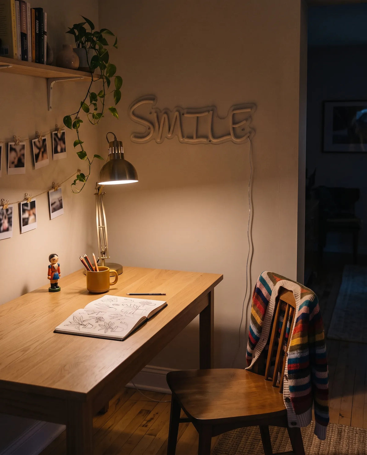 Néon smile éteint dans un coin bureau le soir, étagère de livres, plante retombante et chaise en bois