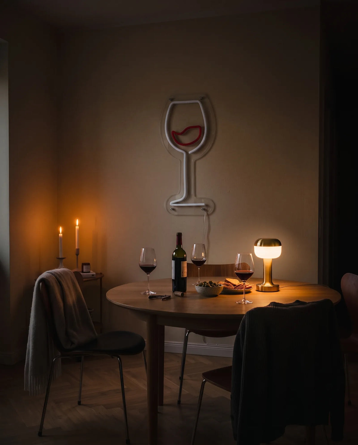 Néon verre de vin éteint dans une salle à manger le soir, table ronde, chaises et lampe dorée