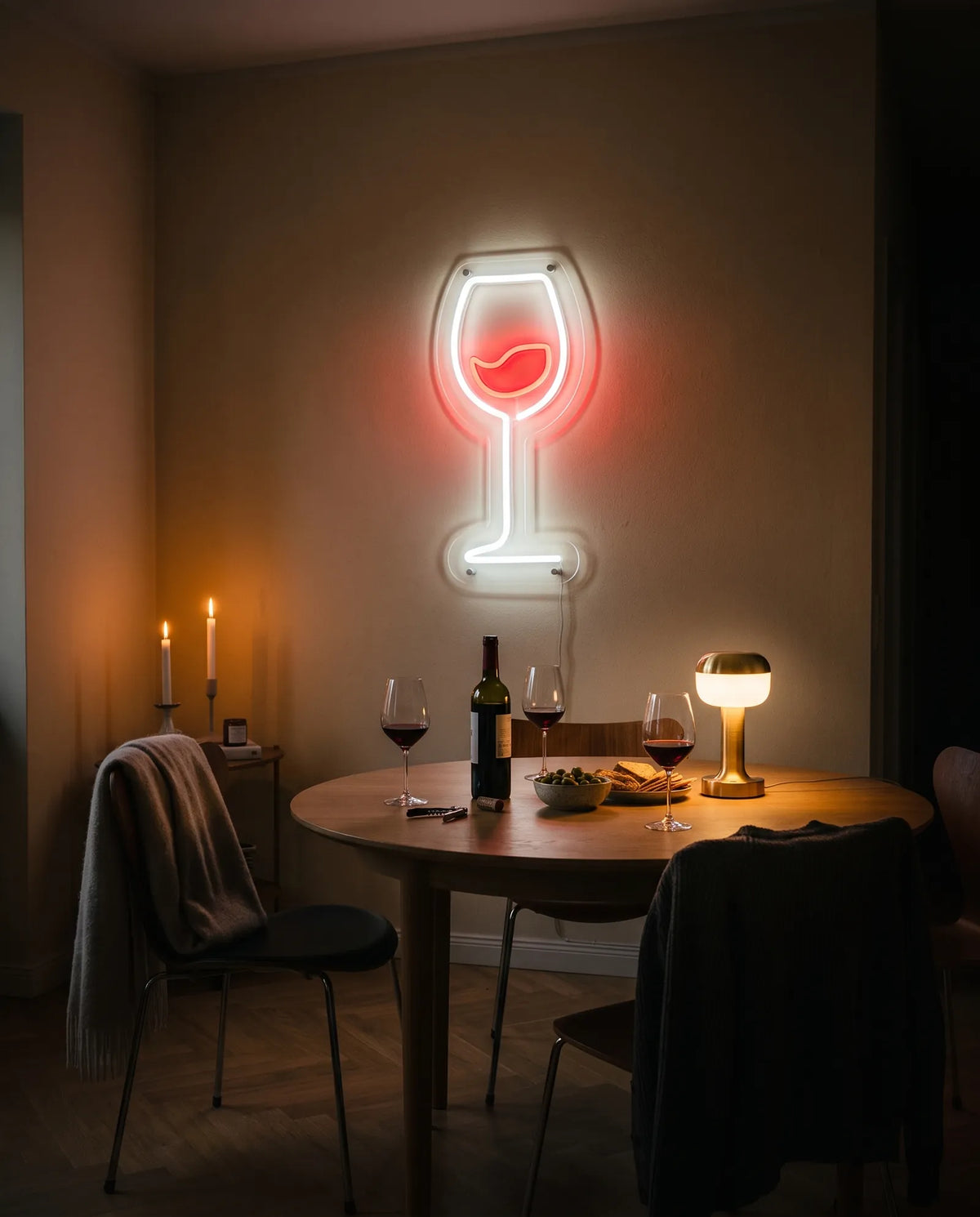 Néon vin blanc et rouge allumé au-dessus d’une table ronde, verres de vin rouge, bouteille, olives et bougies